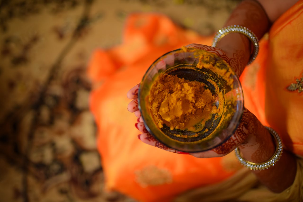 Close-up of a woman's hands holding a bowl of turmeric, showcasing Indian tradition.