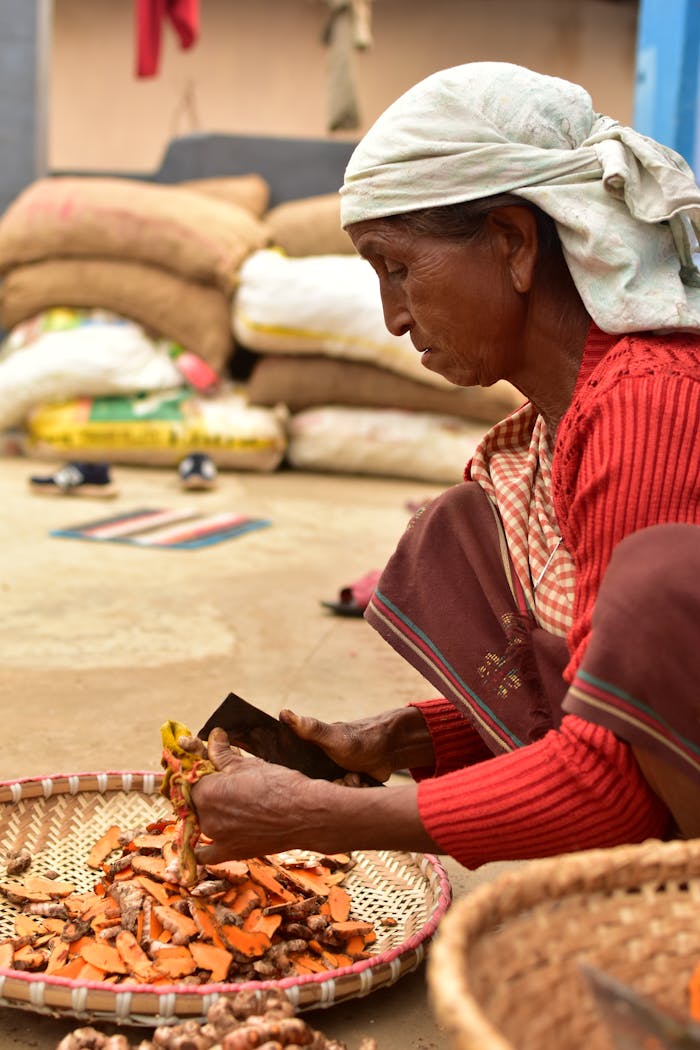 Elderly woman preparing turmeric at a vibrant Indian market in Shillong.