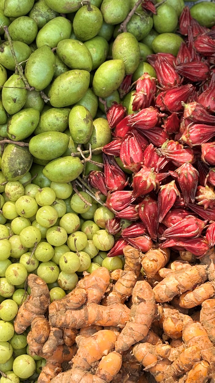 An assortment of fresh amla, roselle, and raw turmeric showcased in a Dhaka market.