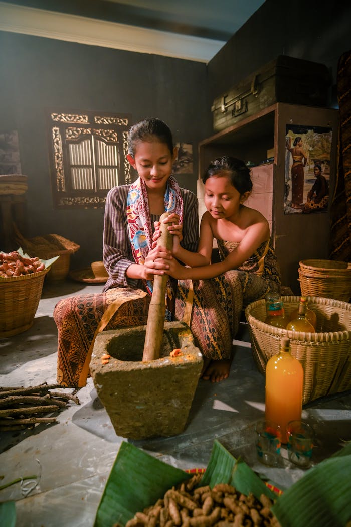 Two people preparing Jamu in a rustic kitchen setting with warm lighting.